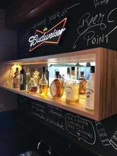 bottles of liquor are lined up on a shelf in front of a chalkboard wall