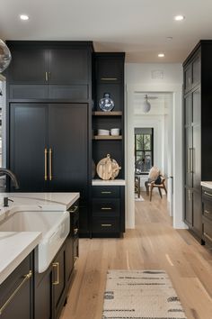 a large kitchen with black cabinets and white counter tops on the floor, along with an area rug