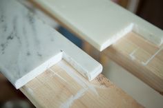 two pieces of white marble sitting on top of a wooden table