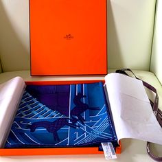 an orange box with a blue and purple scarf in it sitting on a white surface