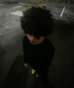 a woman with black hair standing in the middle of an empty parking lot at night