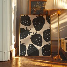 a lamp is sitting next to a painting on the floor with strawberries in black and white