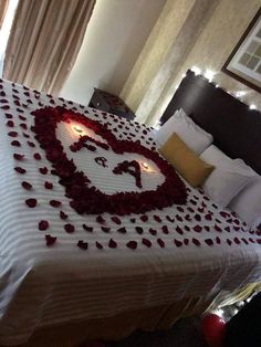 a bed decorated with roses and candles in the shape of a heart