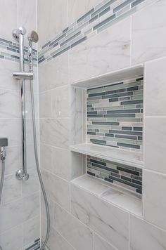 a bathroom with white and gray tiles on the shower wall, shelves in the corner