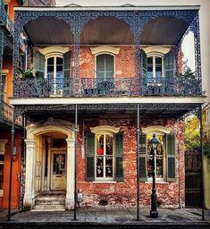 an old brick building with green shutters and balconies on the second story