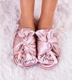 the feet of a woman wearing pink slippers with personalized names on them and bows