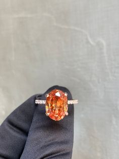 an orange and white diamond ring in someone's hand