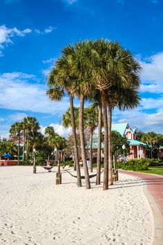 palm trees on the beach in front of a building and blue sky with white clouds