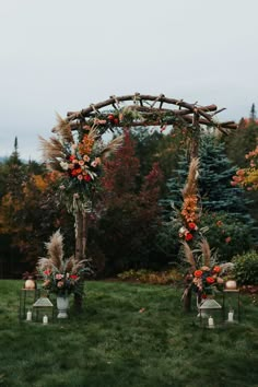 an outdoor ceremony setup with flowers, candles and greenery on the grass in front of trees