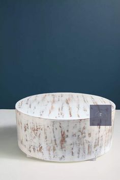 a white and brown marble bowl sitting on top of a table next to a blue wall