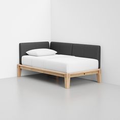 a bed with two pillows on top of it and a white wall in the background