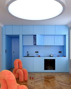 a kitchen with blue cabinets and orange chairs in the middle of wood floored floors