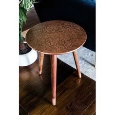 a wooden table sitting on top of a hard wood floor next to a potted plant