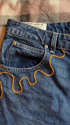 a pair of blue jeans with orange thread on them