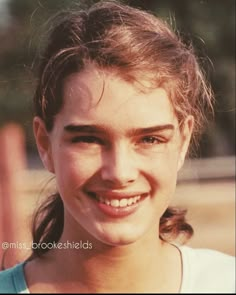 a close up of a person with a smile on their face and hair in a ponytail