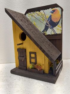 a bird house with a painting on the wall behind it and an open door to another room