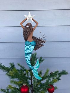 a mermaid figurine sitting on top of a christmas tree