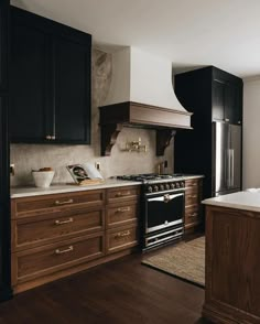 a kitchen with black cabinets and white counter tops is pictured in this image, there are wooden drawers on either side of the stove