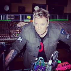 a man sitting in front of a mixing desk with lots of electronic equipment on it