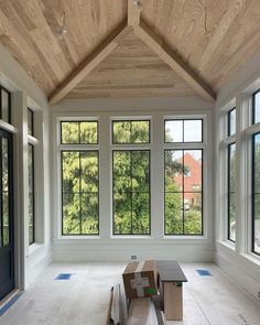 an empty room with large windows and wooden ceiling