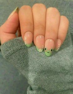 a woman's hand with some green and white nail designs on it, while she is holding her fingers up to the camera