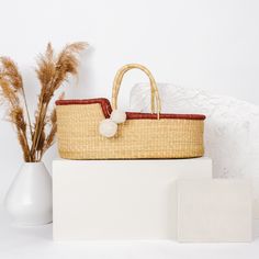 a wicker basket with a pom - pom on it sitting next to a white vase