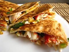 two quesadillas cut in half on a white plate with a woven place mat