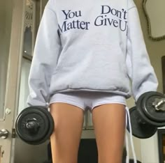 a person with two dumbs on their feet and one leg in the air, wearing a sweatshirt that says you don't matter give up