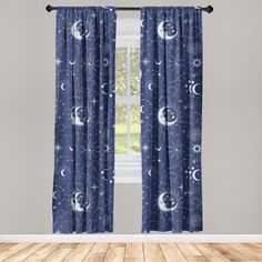 a window curtain with blue and white stars and moon designs on it, in front of a wooden floor