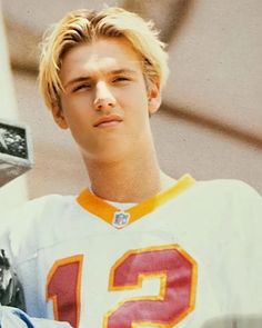 a young man with blond hair and wearing a football uniform