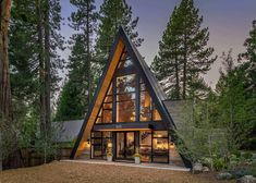 a - frame house in the woods with large windows and lots of trees around it