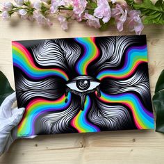 an eye painted on a piece of paper next to flowers