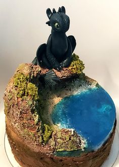 there is a cake that looks like a dragon sitting on top of a mountain with water