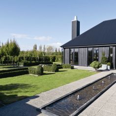 a house with a pond in front of it and some bushes around the back yard