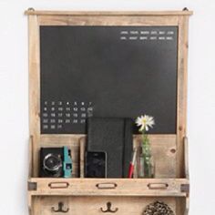 a wooden shelf with some books and other items on it next to a chalkboard