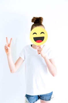 a woman holding up a smiley face mask