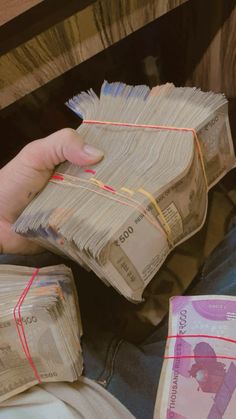 a person is sitting on the floor with stacks of paper money in their hands,