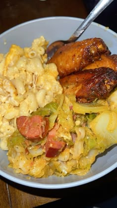 a white plate topped with macaroni and cheese covered in sausages next to meat