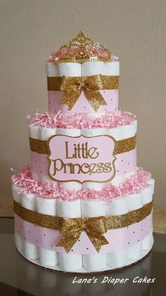 a three tiered cake with pink and gold decorations on it's sides, sitting on top of a table