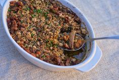 a casserole dish filled with meat and vegetables on top of a cloth covered table