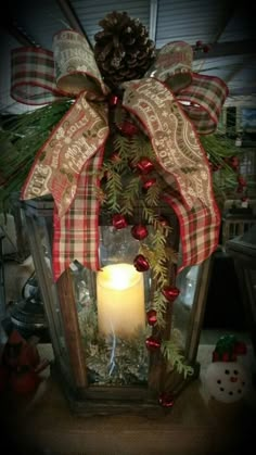 a lighted lantern with a pine cone and red berries on it, decorated for christmas