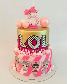 a pink and gold birthday cake with lol surprise on top