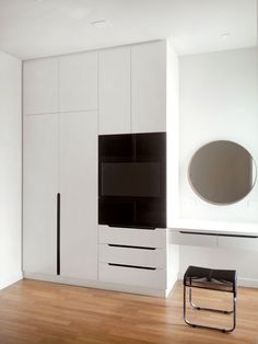 an empty room with white cupboards and black accents on the wall, along with a mirror