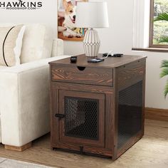 a dog crate sitting next to a couch in a living room with a lamp on top