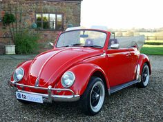 an old red car parked in front of a brick building