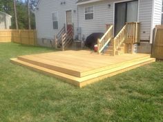 a wooden deck in front of a house with stairs leading up to the back door