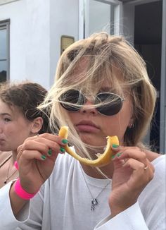 a woman wearing sunglasses holding a banana in front of her face