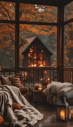 a cozy room with candles and blankets in front of a large window that looks out onto the woods