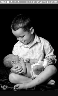 a young boy holding a baby in his arms