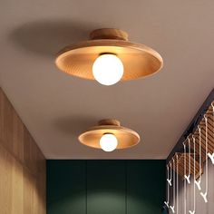 three circular lights are hanging from the ceiling in a hallway with green walls and wood paneling